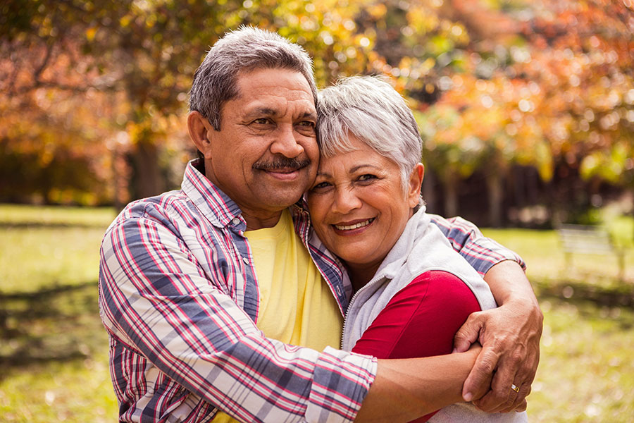 Medicare - Closeup Portrait of a Cheerful Elderly Couple Hugging Each Other While Standing in the Park During the Fall