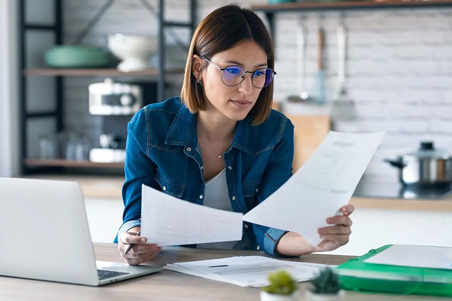 Request Certificate - Woman Working from her Kitchen Table Gathering Insurance Documents